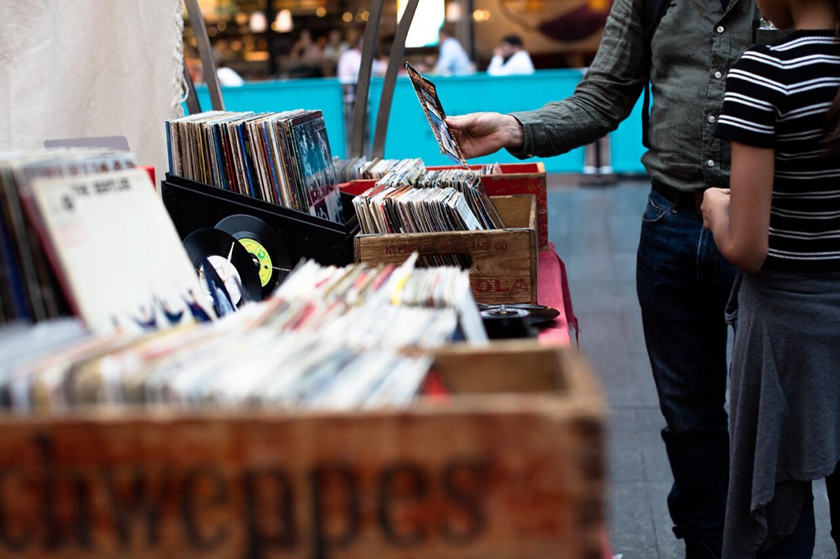 Person bläddrar bland vinylskivor i trälådor på en marknad